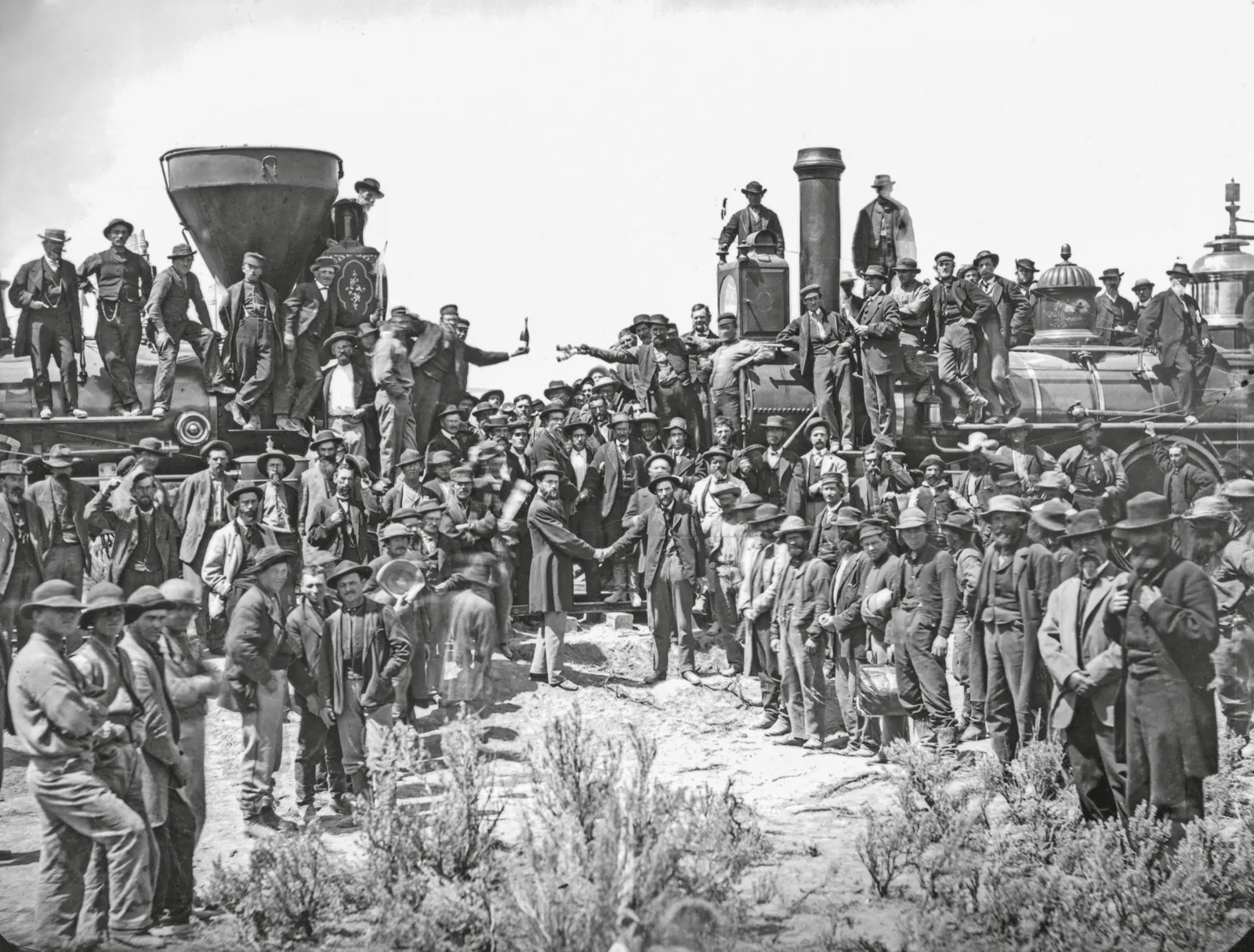1869年5月10日，犹他州Promontory，铁路工人和官员聚集在两列蒸汽机车之间，庆祝金钉仪式。